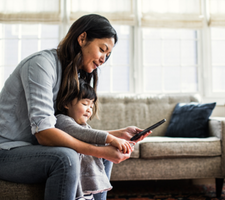 A woman and child looking at a cell phone.